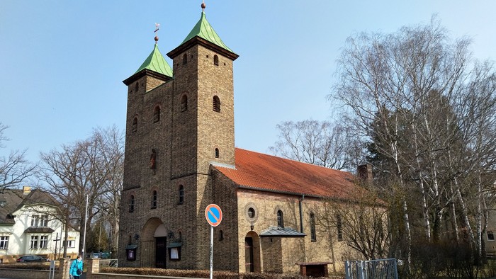 Alte Kirche mit zwei Türmen und rotem Dach an der Straße