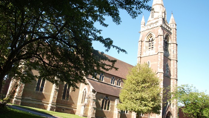 Church with tall spire and surrounding trees.