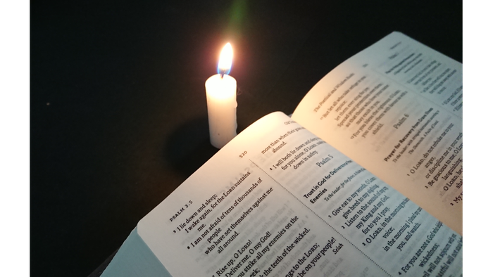 Open book with lit candle nearby