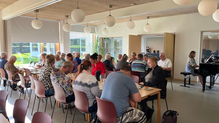En gruppe af mennesker sidder i en lys og moderne lokalitet og deltager i en aktivitet.