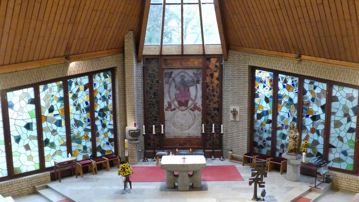 Die Kirche hat bunte Glasfenster und Holzbänke.