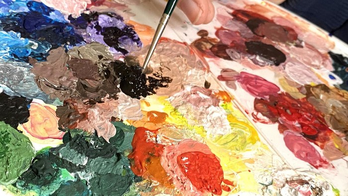 Eine Palette mit verschiedenen Farbtönen und ein Pinsel.