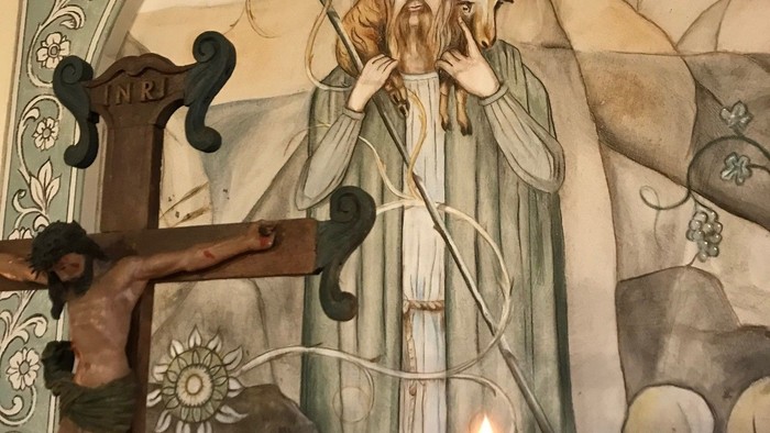 Religiöses Wandgemälde mit Kerze im Vordergrund