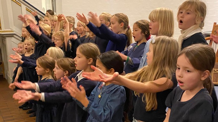 Børn i uniformer, der klapper i en gruppe.