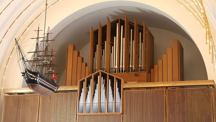 En model af et skib hænger ved et orgel i en kirke.