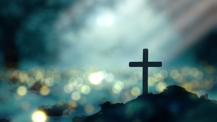 En skygge af et kors foran en lysende himmel.