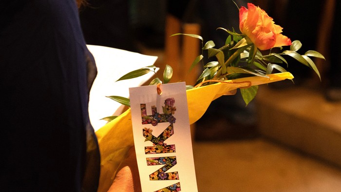 Frau hält Blume mit farbenfrohem Etikett