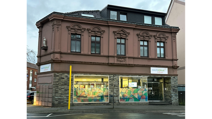 Das Bild zeigt ein mehrstöckiges Gebäude mit einem Geschäft im Erdgeschoss.