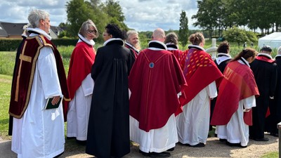 En gruppe gejstlige i liturgisk påklædning samles udendørs til en religiøs procession eller ceremoni.
