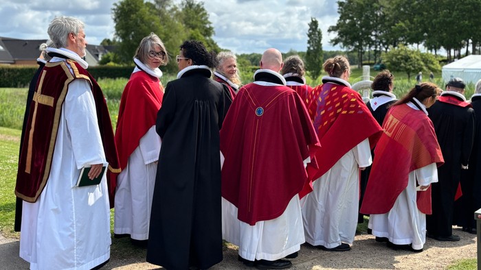En gruppe gejstlige i liturgisk påklædning samles udendørs til en religiøs procession eller ceremoni.