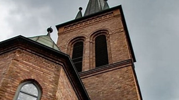 Das Bild zeigt einen Ziegelbau mit spitzen Türmen und Bogenfenstern.