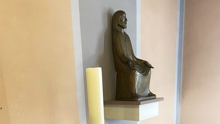 Bronzeplastik eines sitzenden Mannes im langen Gewandauf auf Konsole.