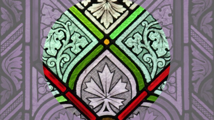 Das Bild zeigt ein farbenfrohes Buntglasfenster mit einem Wappen.