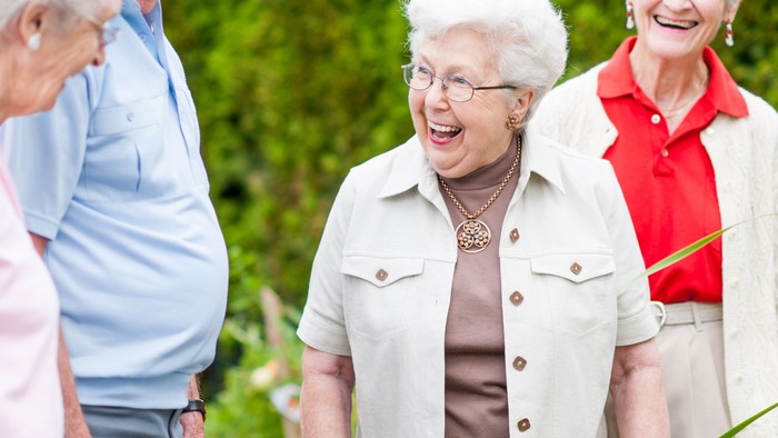 Eine Gruppe älterer Menschen lacht und genießt die Zeit im Freien