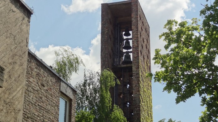 Ein hohes, verwittertes Ziegelgebäude mit einem offenen Turm und umgebenden Bäumen