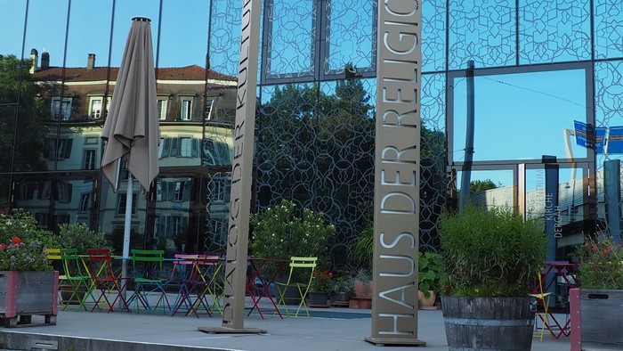 Eingangsbereich des Haus der Religionen. Bern, Europaplatz. Glasfront mit Stelen. Inschrift: Haus der Religionen, haus der Kulturen. 