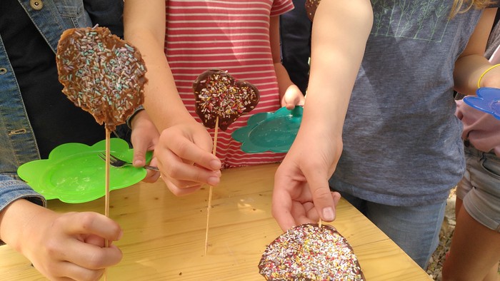 Kinder schmücken Schokoladenherzen mit Streuseln.