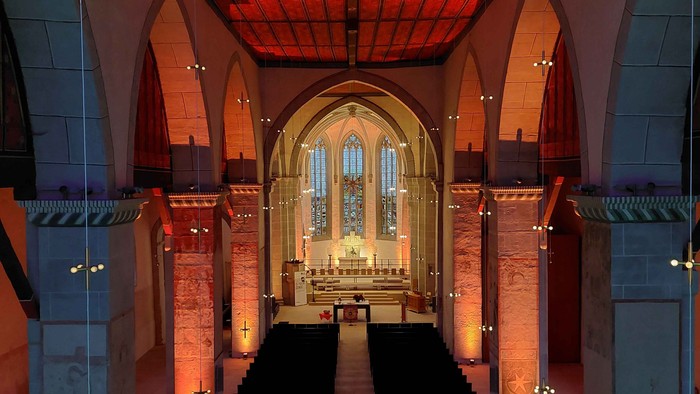 Kircheninneres mit roter Decke und hölzernen Kirchenbänken.