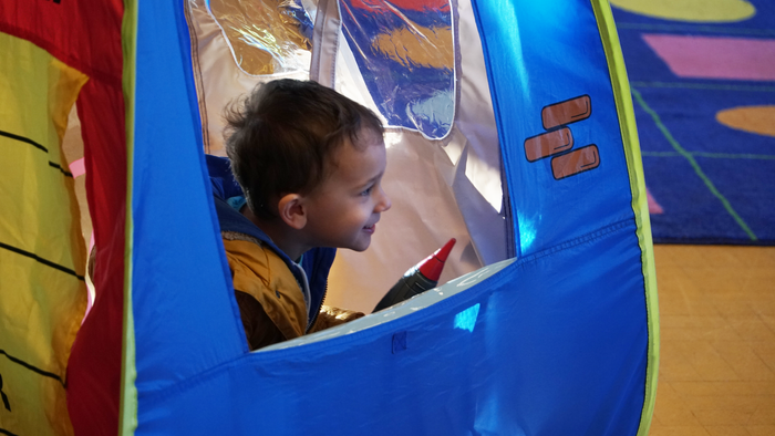 A young boy sits inside a blue inflatable tunnel.