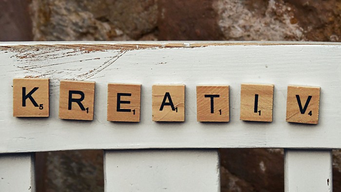 Die Buchstaben K, R, E, A, T, I und V sind auf einem weißen Fensterbrett angeordnet