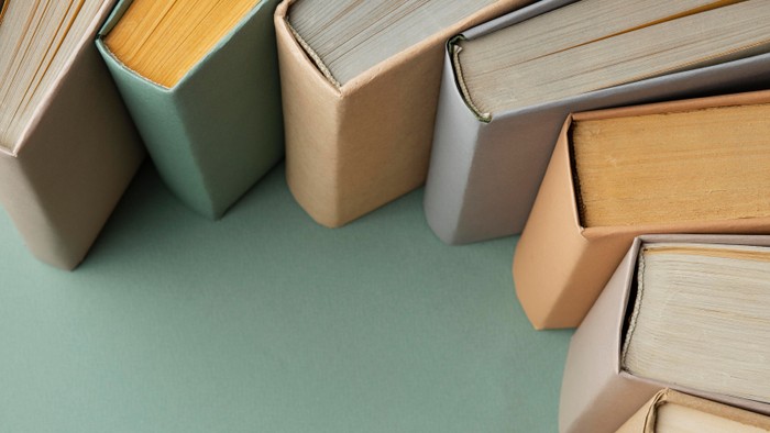 En samling bøger i forskellige farver og størrelser placeret på en grøn underlag