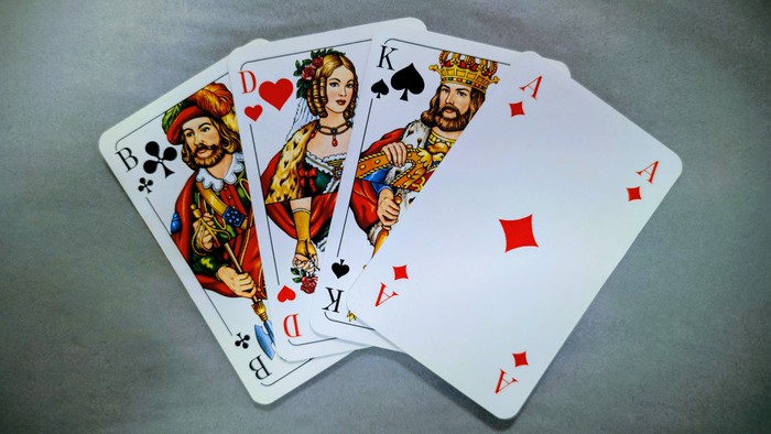 Vier Spielkarten mit Königen und Assen auf grauer Oberfläche