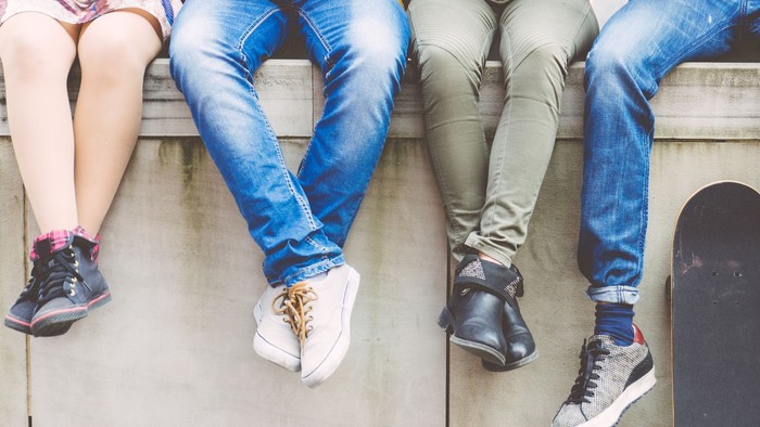 Vier Jugendliche sitzen auf einer Mauer und nutzen ihre Smartphones.