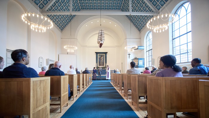 En kirke med folk, der sidder på bænke.