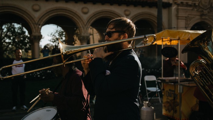 Ein Mann spielt in einer Band Trompete auf der Straße