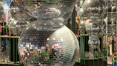 Farverige, forskellige store discokugler arrangeret i en festlig, reflekterende udstilling.