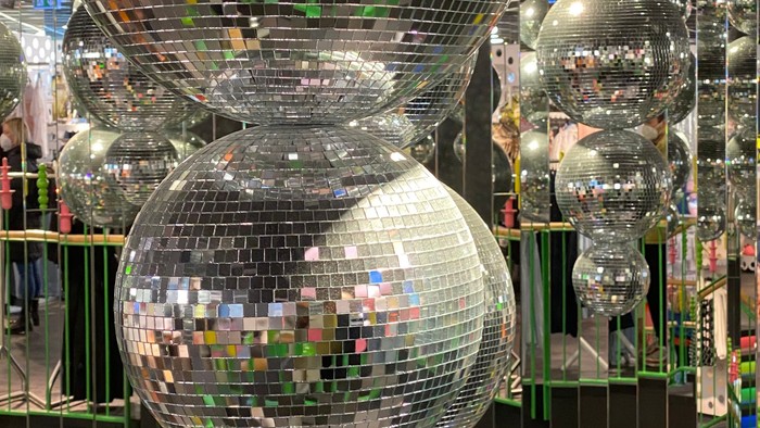 Farverige, forskellige store discokugler arrangeret i en festlig, reflekterende udstilling.