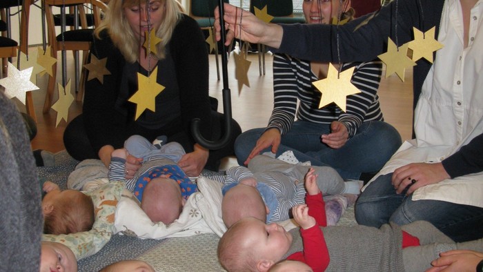 En gruppe kvinder med små børn under en paraply