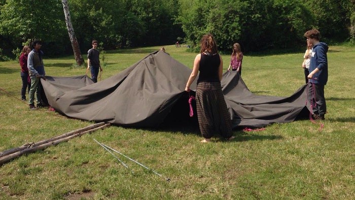 Eine Gruppe von Menschen spannt ein großes Tuch im Freien auf.