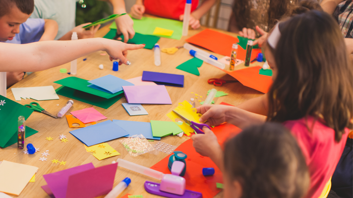 Børn laver papirfluer på bordet