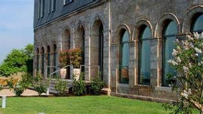 Ein altes Gebäude mit großen Bogenfenstern und gepflegtem Garten.