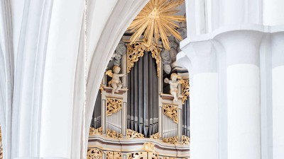 Prächtige Kirchenorgel mit goldenen Verzierungen und weißen Säulen.