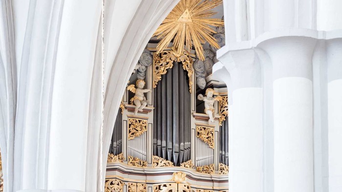 Prächtige Kirchenorgel mit goldenen Verzierungen und weißen Säulen.