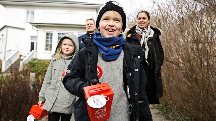 Børn med indsamlingsskøbder går i en kolonne