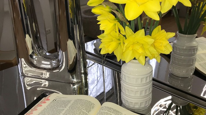 En bog og en vase med gule blomster på en glassidet bord