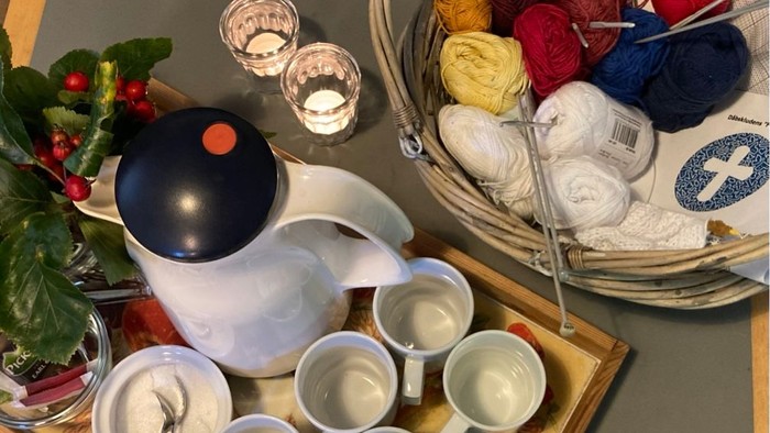 Kaffe kande, kopper, stearinlys på bord og garn i kurv