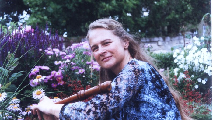 Eine Frau lächelt, während sie ein kleines Kind inmitten eines blühenden Blumengartens hält.