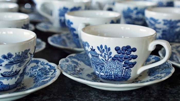 Elegante blaue Teetassen und Unterteller mit Blumenmuster, ordentlich auf einer dunklen Oberfläche arrangiert.