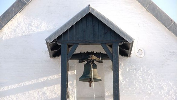 Klokke på Stenum Kirke under et lille tag