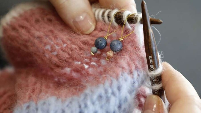 Hænder arbejder med strå og kniplingsspær til at lave en stråket.