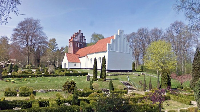En smuk kirke med omgivelser af grønne planter og træer