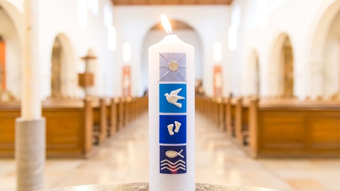 Weiße Kerze mit religiösen Symbolen in Kirchenraum