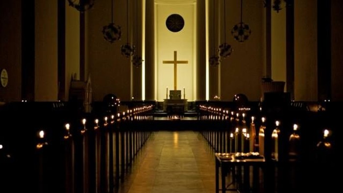 En kirkeinders stille og lysende indersværgelse med lysende lys og centralt kors.