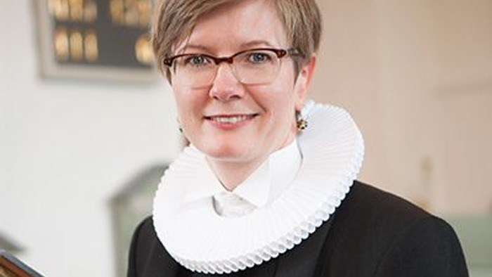 Kvinde i sort jakke og hvid krage.