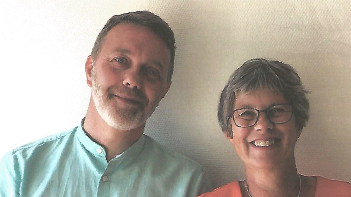 To smilende voksne poser glædeligt sammen indendørs.