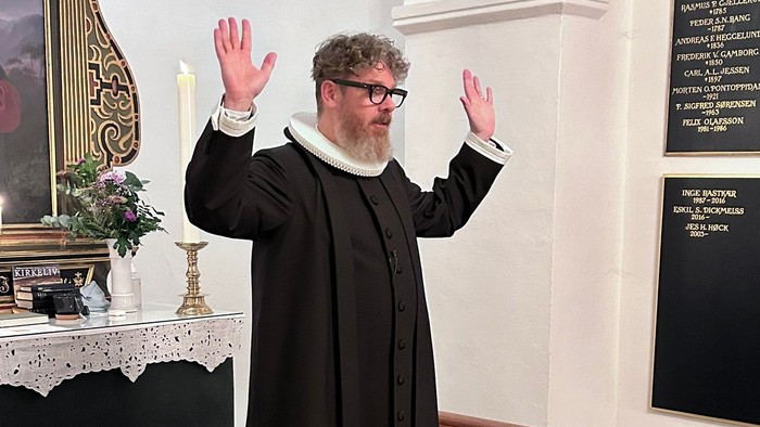 Mand i svart kapittel i kirke.